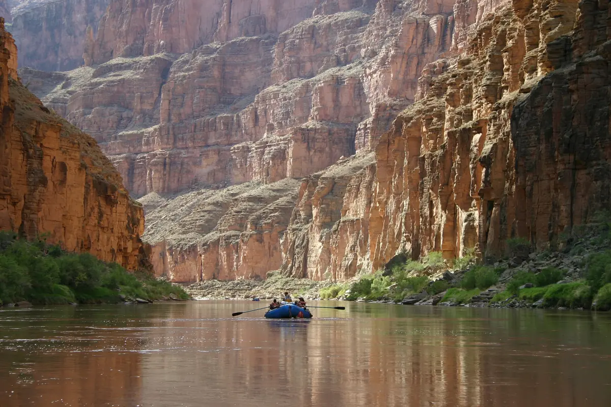Small raft on the calm Colorado River below tall canyon walls