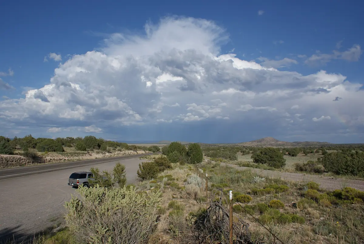 Towering thunderstorm clouds over a desert highway in northwest Arizona