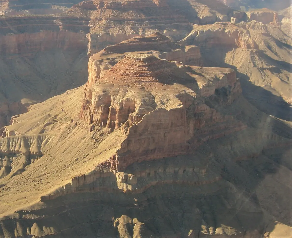 Helicopter view of a sunlit sandstone butte rising inside the Grand Canyon
