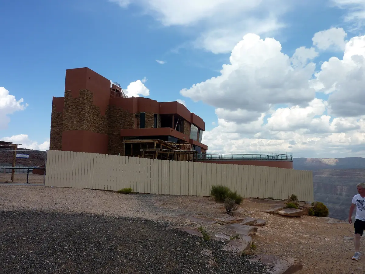 Red-brown Skywalk entrance building at the canyon edge beneath big clouds