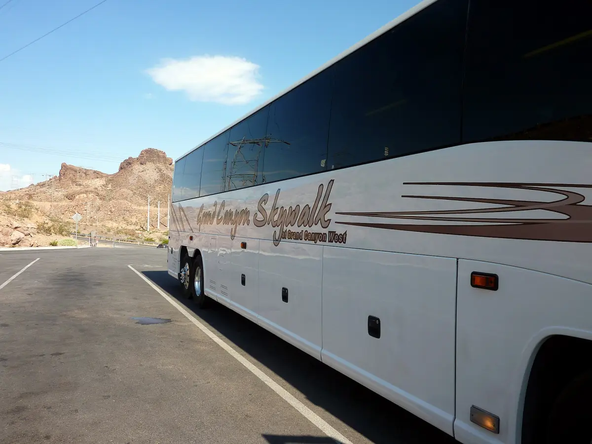 Tour coach parked at a desert stop with red rocks behind it